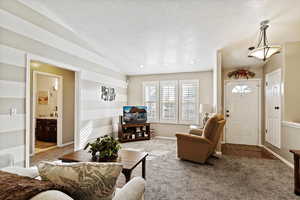 Carpeted living room with lofted ceiling and a textured ceiling