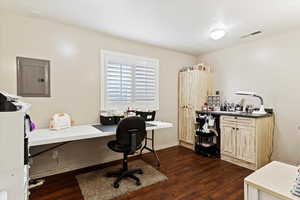 Office area featuring electric panel and dark hardwood / wood-style floors