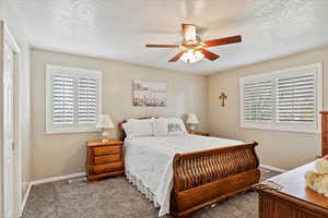 Carpeted bedroom featuring a textured ceiling and ceiling fan