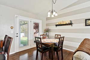 Dining space with dark wood-type flooring and an inviting chandelier