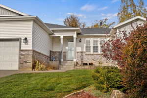 View of exterior entry featuring a garage and a yard