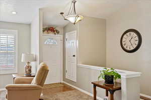 Entrance foyer with hardwood / wood-style floors, a textured ceiling, and lofted ceiling