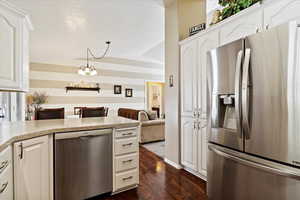 Kitchen with white cabinets, appliances with stainless steel finishes, dark hardwood / wood-style floors, and lofted ceiling