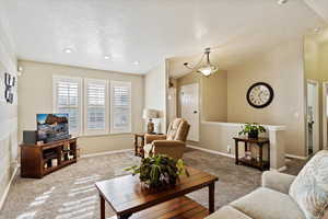 Living room with vaulted ceiling, carpet floors, and a textured ceiling