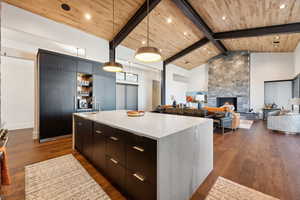 Kitchen featuring dark hardwood flooring, decorative light fixtures, and a large island