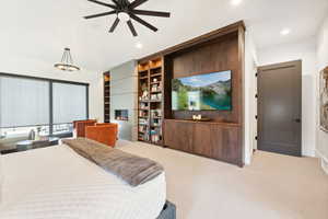 Bedroom featuring ceiling fan with notable chandelier, a fireplace, and light carpet