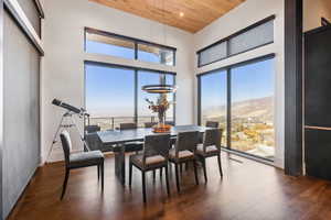 Dining area with hardwood floors, wooden ceiling, a high ceiling, and mountain view