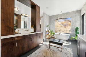 Bathroom with tile patterned flooring, vanity, a tub to relax in, and tile walls