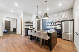 Kitchen featuring pendant lighting, stainless steel appliances, a breakfast bar area, and light hardwood / wood-style flooring