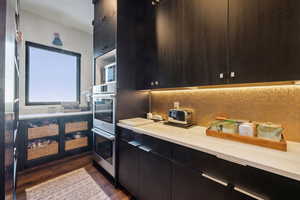 Kitchen featuring backsplash, dark hardwood flooring, and stainless steel double oven