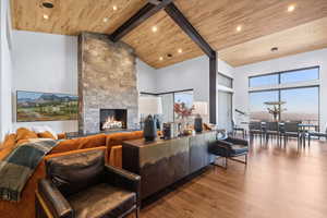 Living room with beam ceiling, hardwood flooring, high vaulted ceiling, and wood ceiling