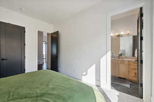 Bedroom featuring connected bathroom, sink, and carpet