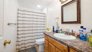 Bathroom with tile patterned flooring, vanity, curtained shower, and toilet