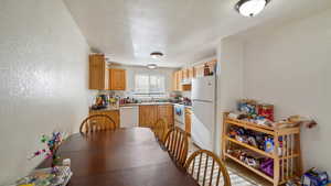 Kitchen with a textured ceiling, white appliances, and sink