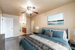 Bedroom with light wood-type flooring, ceiling fan, and connected bathroom