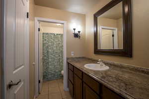 Bathroom featuring tile patterned flooring, a shower with curtain, vanity, and toilet