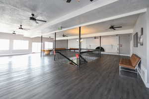 Recreation room with beamed ceiling, a textured ceiling, and hardwood / wood-style flooring