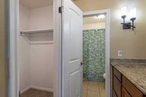 Bathroom with tile patterned floors, toilet, vanity, and walk in shower