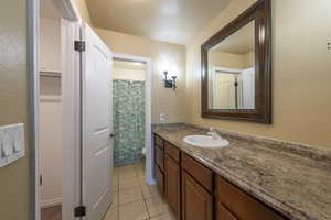 Bathroom with tile patterned floors, toilet, vanity, and a shower with shower curtain