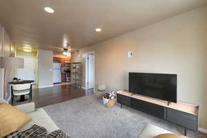 Living room featuring ceiling fan and dark wood-type flooring