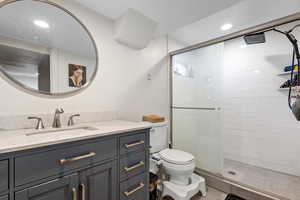 Bathroom with vanity, toilet, and an enclosed shower