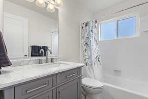 Full bathroom featuring vanity, shower / bathtub combination with curtain, and toilet