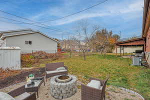 View of yard featuring a gazebo, cooling unit, and an outdoor living space with a fire pit