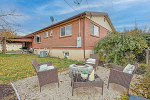 Rear view of property with a yard, an outdoor fire pit, and central AC