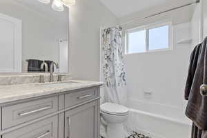 Full bathroom with vanity, shower / bath combination with curtain, and toilet