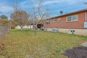 Back of property with a yard and central AC