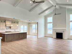 Kitchen featuring light hardwood / wood-style floors, high vaulted ceiling, a wealth of natural light, and a center island with sink