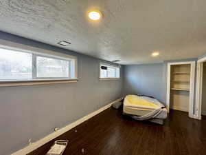 Unfurnished bedroom with dark wood-type flooring and a textured ceiling