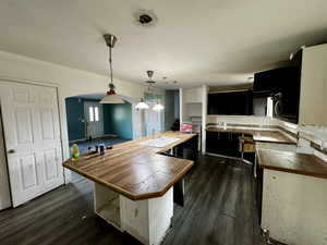 Kitchen featuring pendant lighting, sink, decorative backsplash, dark hardwood / wood-style flooring, and kitchen peninsula