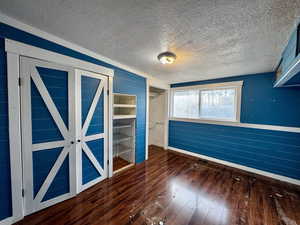 Empty room featuring a textured ceiling and dark hardwood / wood-style floors