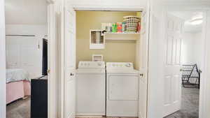 Laundry room with washing machine and clothes dryer and carpet flooring