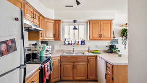 Kitchen with decorative light fixtures, white appliances, and sink