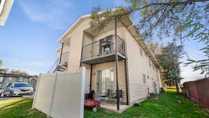 Back of property with a balcony and a yard