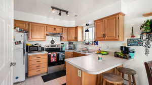 Kitchen with sink, kitchen peninsula, pendant lighting, a kitchen bar, and appliances with stainless steel finishes