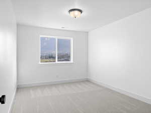 Empty room with light colored carpet and a textured ceiling