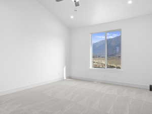 Empty room featuring light carpet, ceiling fan, and lofted ceiling