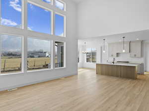 Unfurnished living room with a mountain view, sink, light hardwood / wood-style flooring, a towering ceiling, and a chandelier