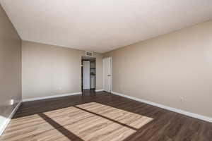 Spare room featuring a textured ceiling and dark wood-type flooring