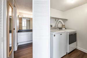 Laundry area featuring a textured ceiling, washing machine and dryer, and dark hardwood / wood-style floors