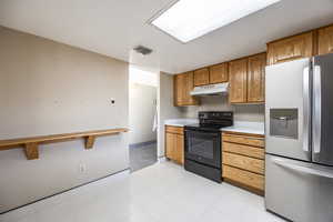 Kitchen featuring stainless steel fridge and black electric range oven