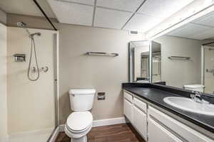 Bathroom with walk in shower, a drop ceiling, vanity, hardwood / wood-style flooring, and toilet