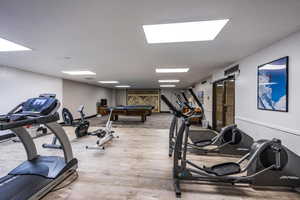 Exercise room with light wood-type flooring and billiards