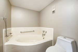 Bathroom featuring a tub to relax in and toilet