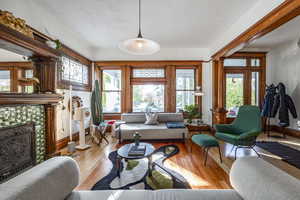 Living room featuring ornate columns, a tile fireplace, and light hardwood / wood-style flooring