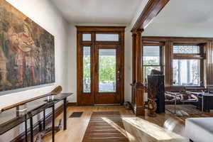 Entrance foyer with light hardwood / wood-style flooring, a healthy amount of sunlight, and ornate columns