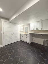 Basement laundry area featuring cabinets, hookup for a washing machine, a textured ceiling, and electric dryer hookup